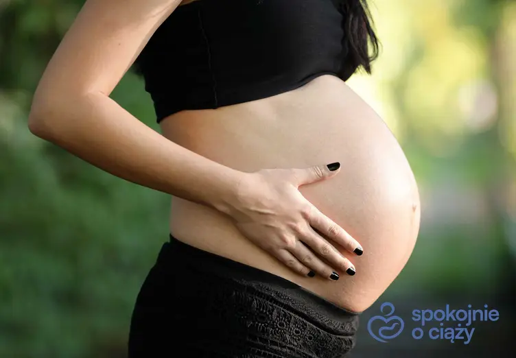 Kobieta w ciąży trzymająca się za brzuch, a także przepuklina pępkowa w ciąży i jej przyczyny oraz objawy