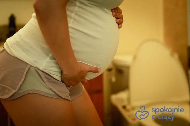 Kobieta w zaawansowanej ciąży trzymająca się za brzuch przy toalecie, a także biegunka w ciąży