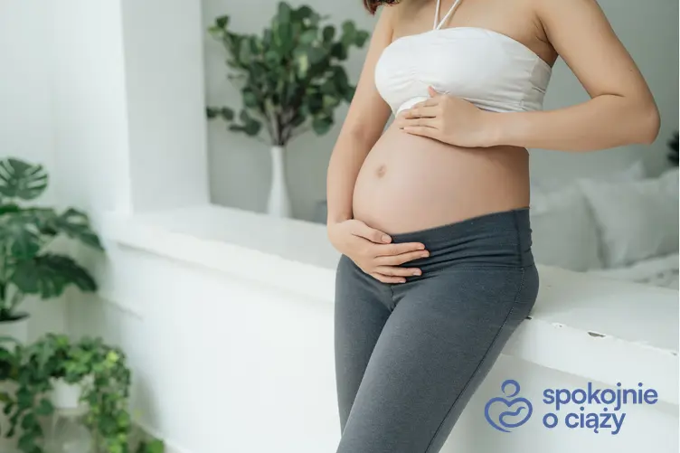 Kobieta w ciąży trzymająca się za brzuch, a także 9 tydzień ciąży krok po kroku