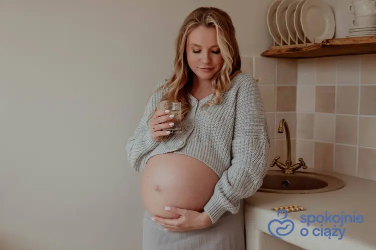 Kobieta w ciąży w kuchni pijąca wodę, a także wapń w ciąży krok po kroku
