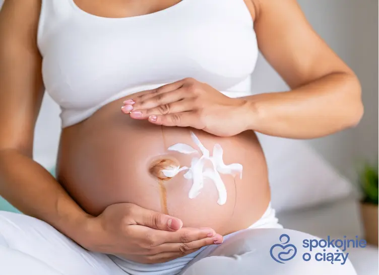 Kobieta w zaawansowanej ciąży balsamująca brzuszek, a także kosmetyki dla kobiet w ciąży