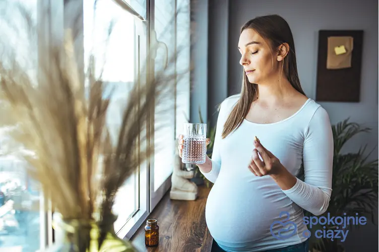 Kobieta w zaawansowanej ciąży trzymająca tabletkę i wodę, a także żurawina w ciąży