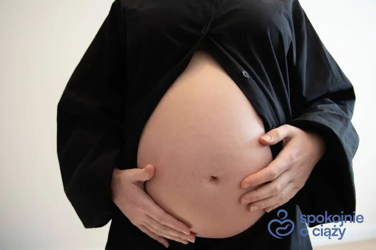 Kobieta w zaawansowanej ciąży trzymająca się za brzuch, a także 26 tydzień ciąży krok po kroku