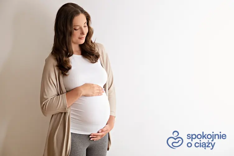 Kobieta w zaawansowanej ciąży trzymająca się za brzuch, a także 29 tydzień ciąży krok po kroku