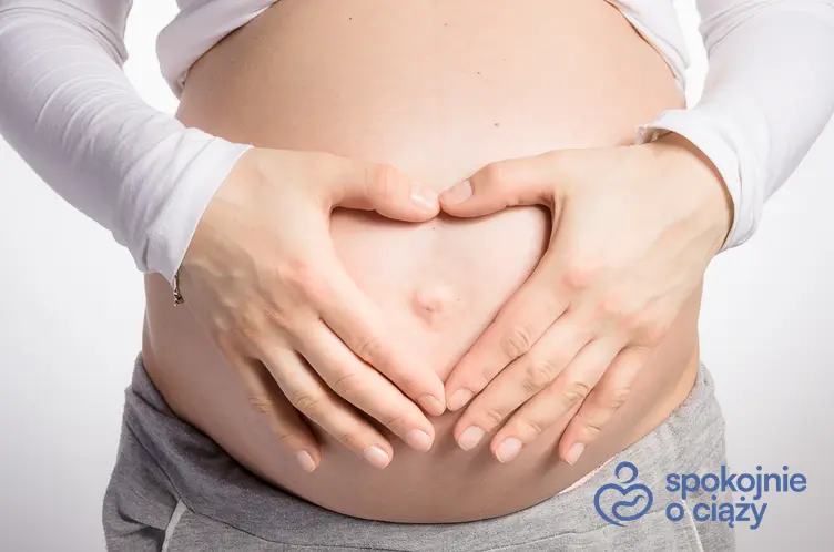 Kobieta w zaawansowanej ciąży trzymająca się za brzuch, a także informacje, który to tydzień ciąży