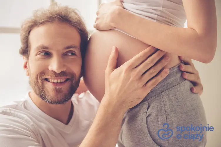 Kobieta w zaawansowanej ciąży z uchem partnera przy brzuchu, a także 33 tydzień ciąży krok po kroku