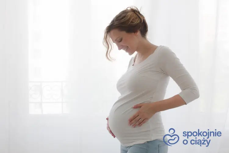 Kobieta w zaawansowanej ciąży trzymająca się za brzuch oraz porady, czy można jeść krewetki w ciąży