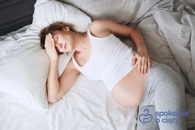 Kobieta w zaawansowanej ciąży leżąca w łóżku oraz wzdęcia w ciąży