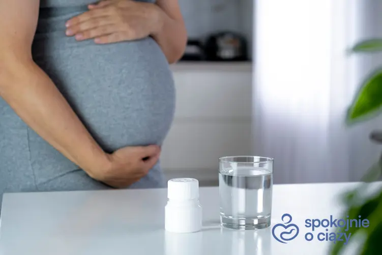 Kobieta w zaawansowanej ciąży obok leków i szklanki wody oraz czy Aspargin można stosować w ciąży