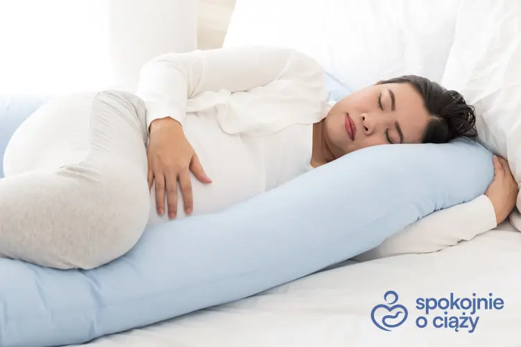Kobieta w zaawansowanej ciąży śpiąca na poduszcze rogal, a także porady, na którym boku spać w ciąży