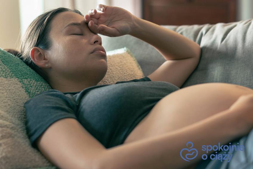 Kobieta w zaawansowanej ciąży z dużym brzuchem trzymająca się za głowę, a także ból głowy w ciąży krok po kroku