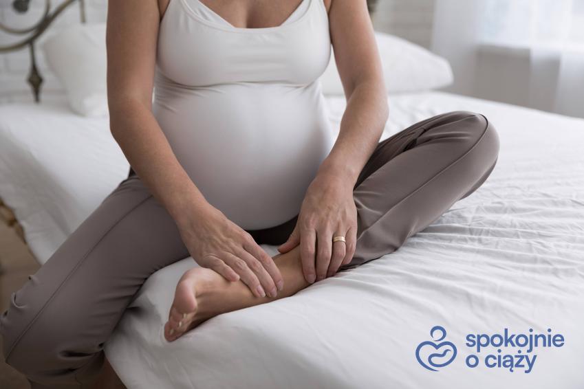 Kobieta w zaawansowanej ciąży siedząca i trzymająca się na łydkę, a także spuchnięte nogi w ciąży