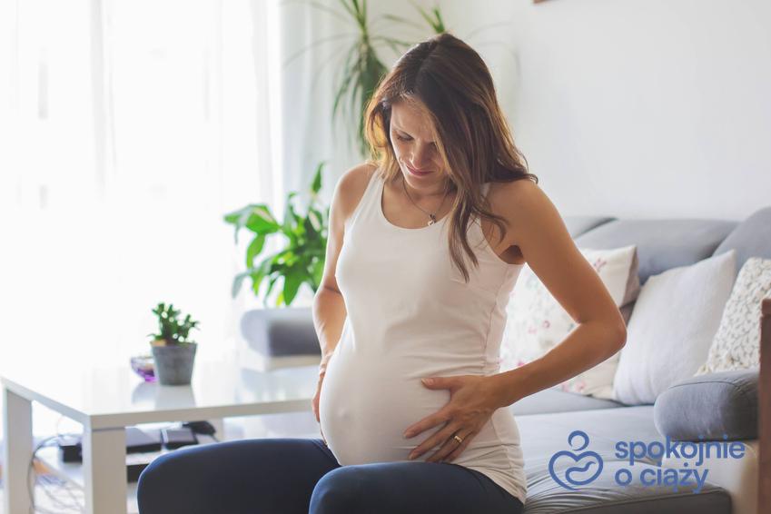 Kobieta w zaawansowanej ciąży trzymająca się za brzuch, a także ból podbrzusza w ciąży krok po kroku
