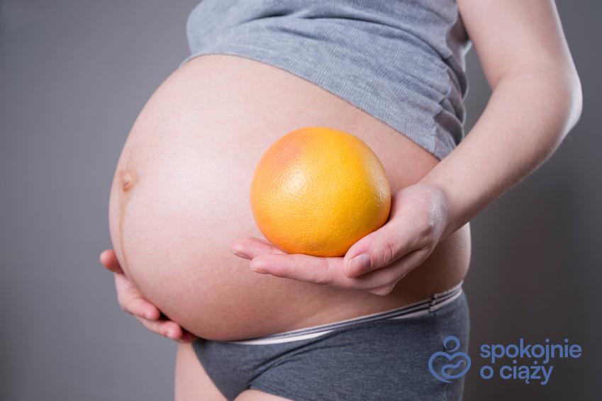 Kobieta w zaawansowanej ciąży trzymająca grejpfruta przy brzuchu, a także grejpfrut w ciąży bez tajemnic