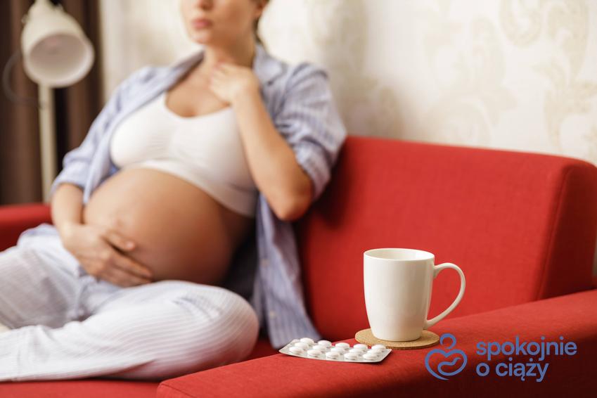 Kobieta w zaawansowanej ciąży siedząca na kanapie i trzymająca się za gardło, a także ból gardła w ciąży