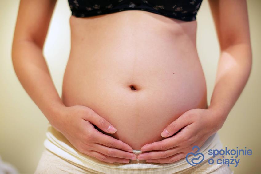 Kobieta w ciąży trzymająca się za brzuch, a także 7 tydzień ciąży krok po kroku