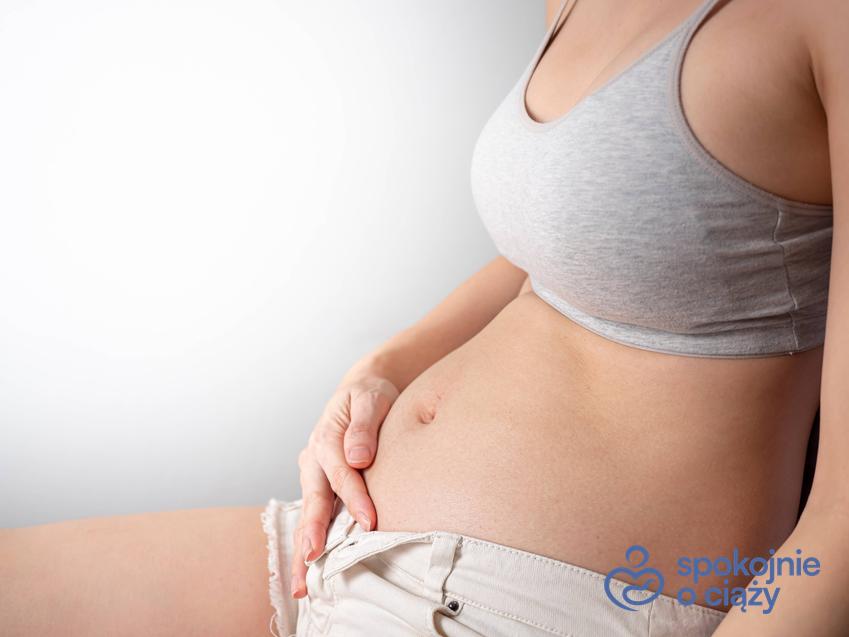 Kobieta w ciąży podtrzymująca brzuszek, a także informacje, jak wygląda 7 tydzień ciąży bez tajemnic