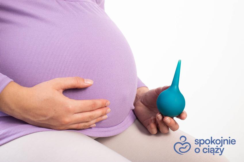 Kobieta w zaawansowanej ciąży trzymająca gruszkę do lewatywy, a także lewatywa przed porodem bez tajemnic
