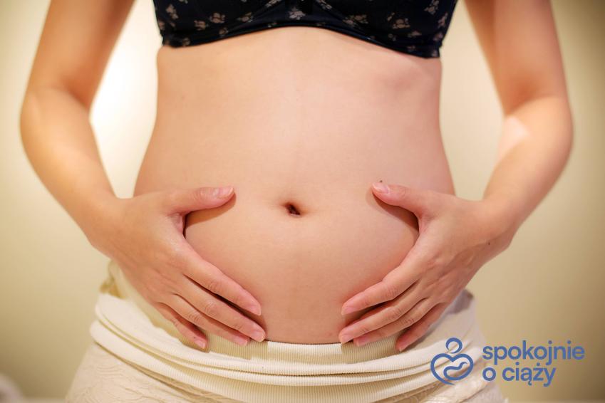 Kobieta eksponująca brzuszek w 12 tygodniu ciąży, a także 12 tydzień ciąży i jego przebieg krok po kroku