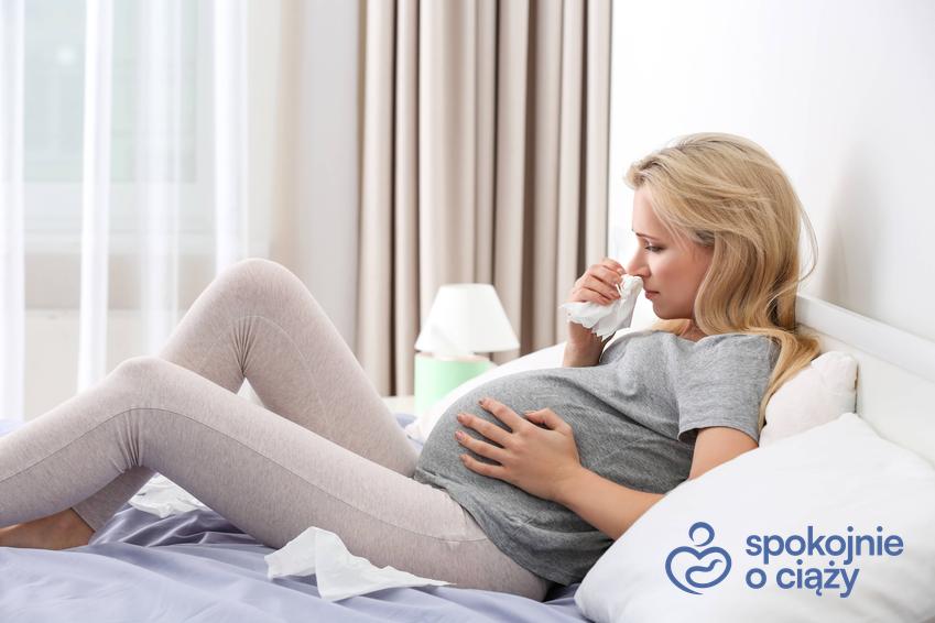 Kobieta w zaawansowanej ciąży leżąca chora w łóżku z katarem, a także jak leczyć katar w ciąży krok po kroku