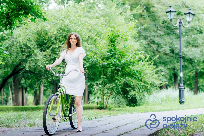 Kobieta w zaawansowanej ciąży w białej sukience na rowerze, a także czy w ciąży można jeździć na rowerze