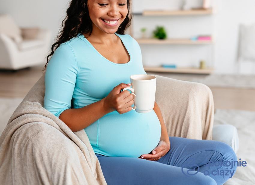 Kobieta w zaawansowanej ciąży na sofie z kubkiem melisy, a także melisa w ciąży bez tajemnic