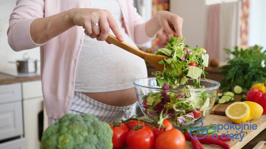 Kobieta robiąca sałatkę, a także jakie są zakazane owoce i warzywa w ciąży, czyli lista zakazanych produktów w czasie ciąży