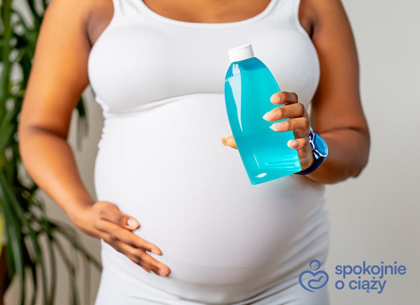 Kobieta w zaawansowanej ciąży trzymająca butelkę, a także płyn do higieny intymnej w ciąży bez tajemnic