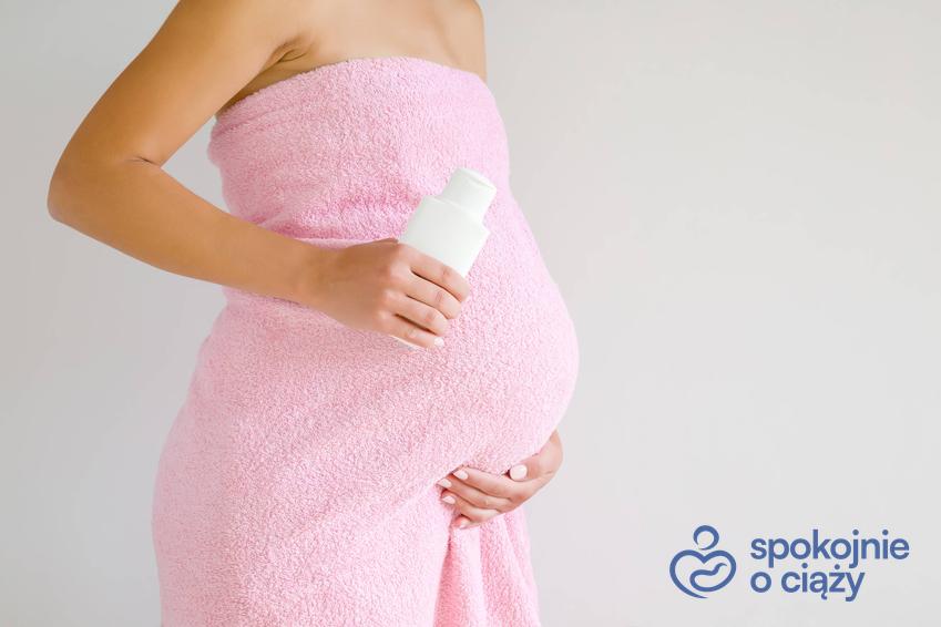 Kobieta w zaawansowanej ciąży owinięta ręcznikiem, a także płyn do higieny intymnej w ciąży krok po kroku