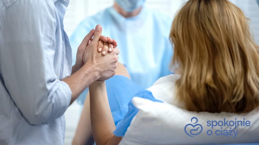 Kobieta w szpitalu podczas porodu trzymana za rękę przez partnera, a także jak wygląda poród krok po kroku okiem położnej